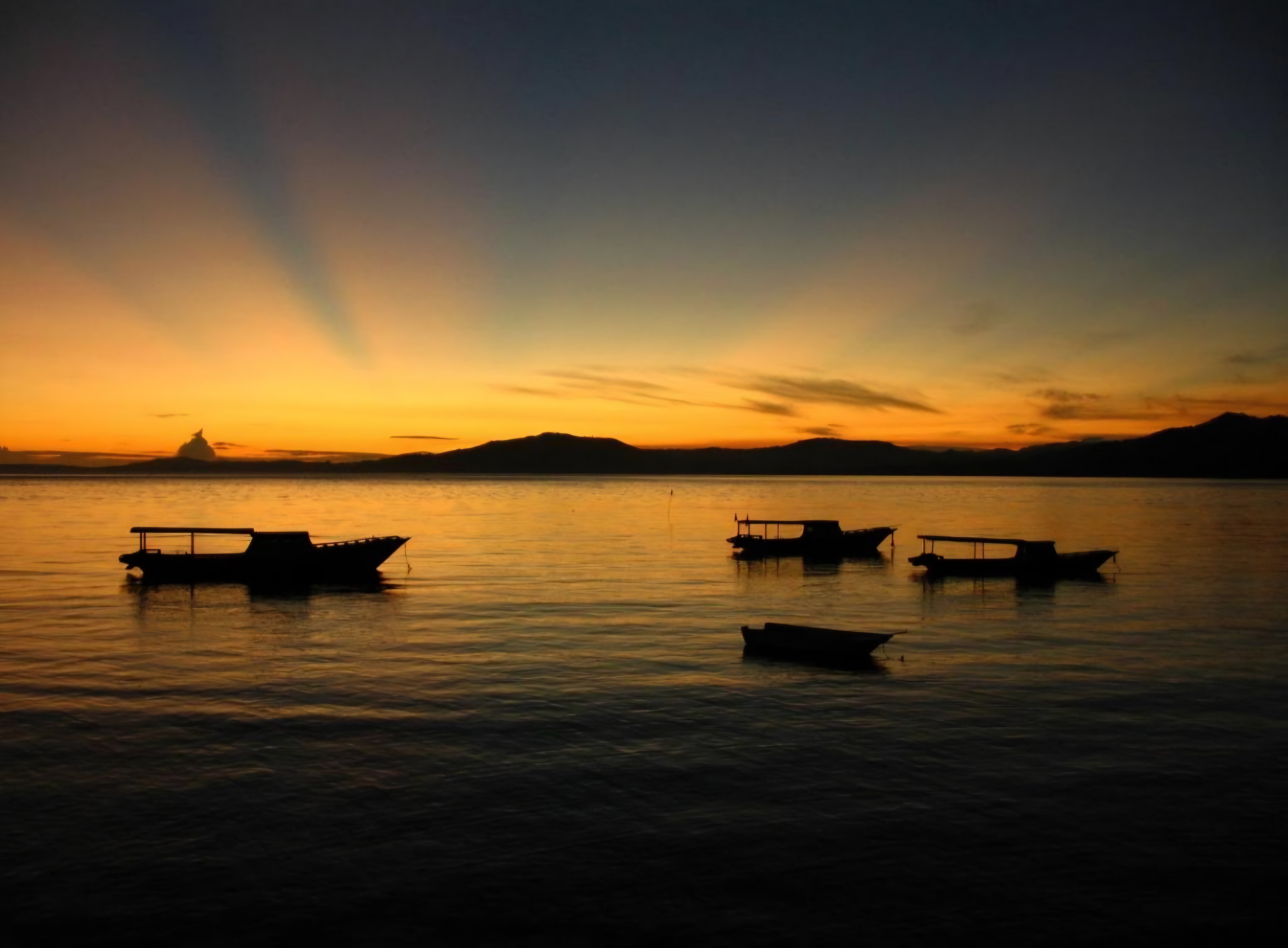 Dive boats moored offshore at sunset